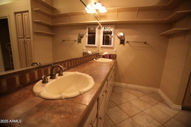 bathroom with double vanity, baseboards, a sink, and tile patterned floors