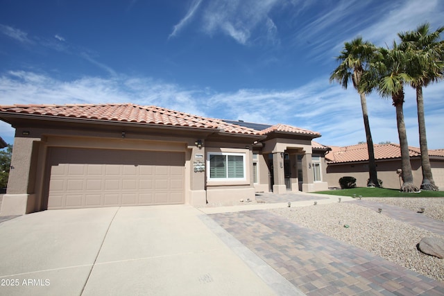 mediterranean / spanish house with an attached garage, driveway, a tile roof, and stucco siding