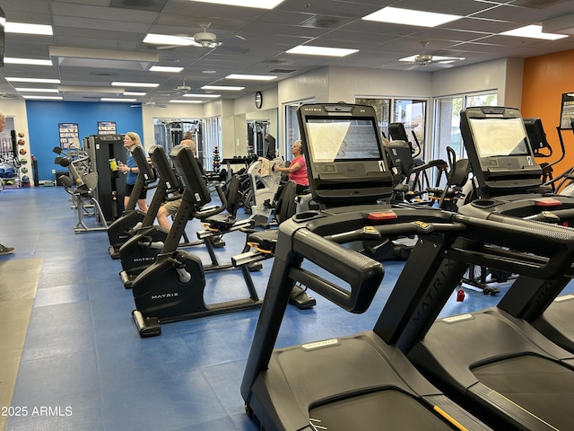 gym with a ceiling fan and a drop ceiling