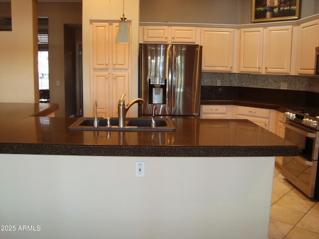 kitchen with light tile patterned floors, stainless steel appliances, a sink, hanging light fixtures, and dark countertops