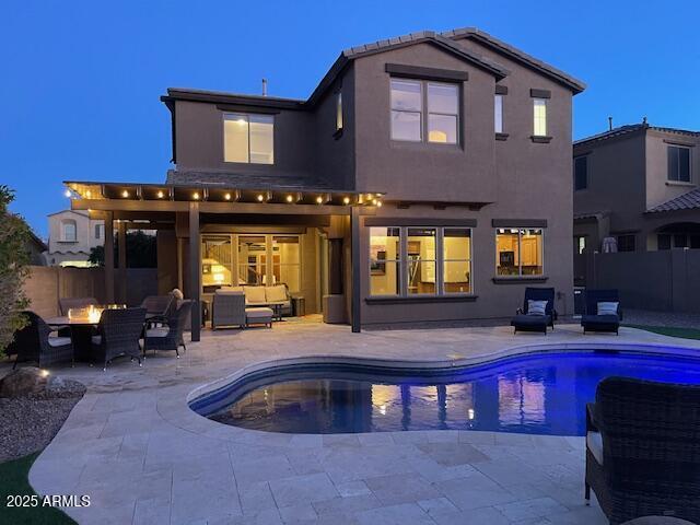 back house at dusk featuring a fenced in pool, an outdoor living space with a fire pit, and a patio