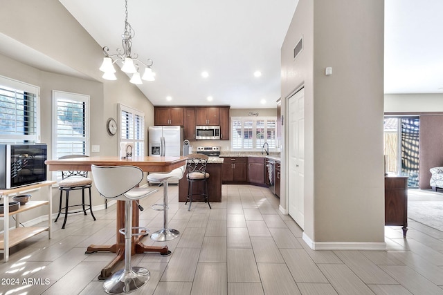 kitchen featuring a center island, stainless steel appliances, pendant lighting, lofted ceiling, and a breakfast bar