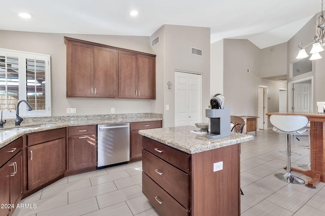 kitchen with a center island, a kitchen bar, sink, hanging light fixtures, and light stone counters