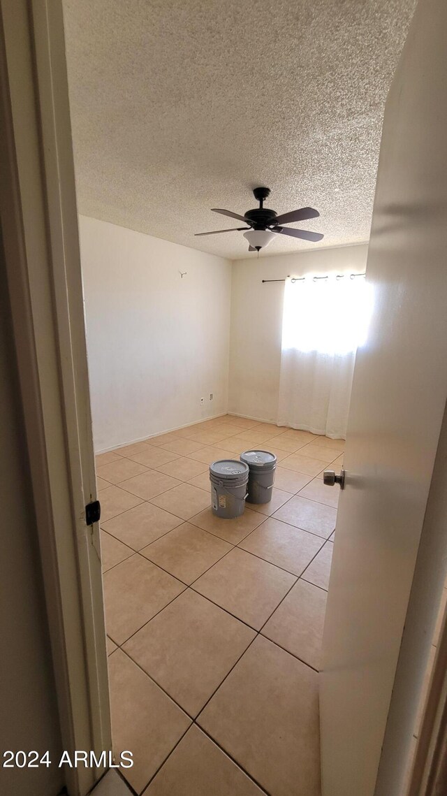 unfurnished bedroom with tile patterned floors, a textured ceiling, a closet, and ceiling fan