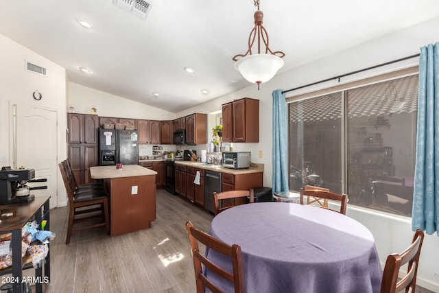 kitchen featuring hardwood / wood-style floors, a center island, lofted ceiling, black appliances, and decorative light fixtures