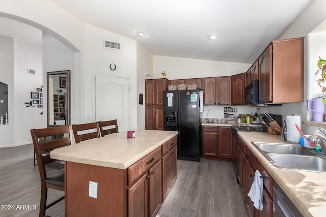 kitchen featuring sink, dark hardwood / wood-style flooring, a breakfast bar, a kitchen island, and black appliances