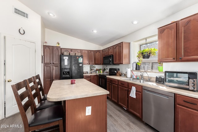 kitchen featuring a center island, lofted ceiling, black appliances, sink, and light hardwood / wood-style flooring