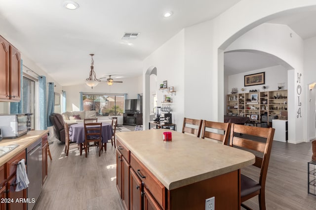 kitchen with ceiling fan, a kitchen island, stainless steel appliances, and light wood-type flooring