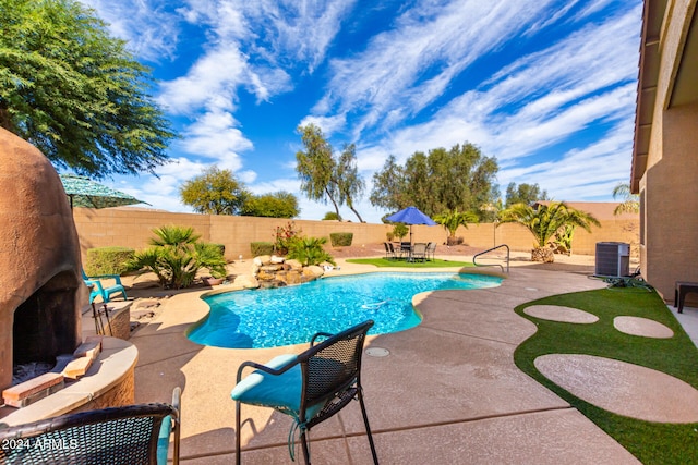 view of swimming pool with cooling unit, a patio, and an outdoor stone fireplace