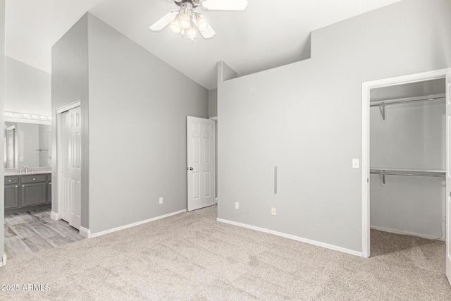 unfurnished bedroom featuring sink, a spacious closet, light colored carpet, and ensuite bath