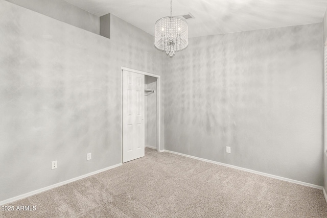 carpeted spare room with an inviting chandelier