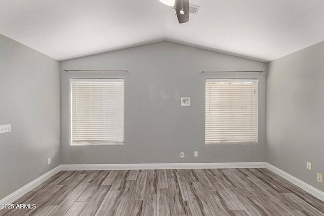 spare room featuring lofted ceiling and light hardwood / wood-style flooring