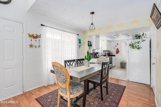 dining space with light wood-type flooring and a textured ceiling