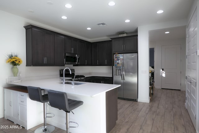 4149 E Appaloosa Rd, Gilbert, AZ 85296 - kitchen with a peninsula, light wood finished floors, stainless steel appliances, recessed lighting, and a breakfast bar area