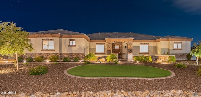 prairie-style home with stone siding, stucco siding, and a gate