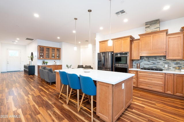 kitchen with a kitchen island, appliances with stainless steel finishes, a breakfast bar area, decorative light fixtures, and light countertops