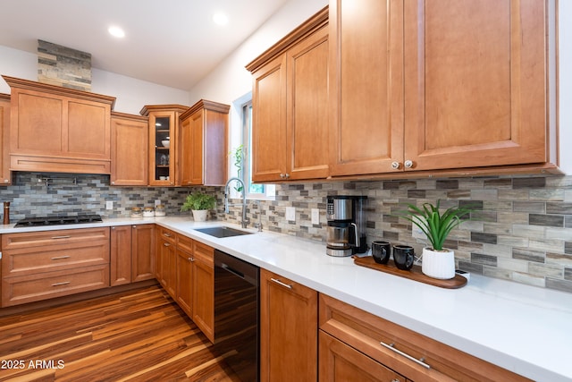 kitchen with a sink, light countertops, black appliances, brown cabinetry, and glass insert cabinets