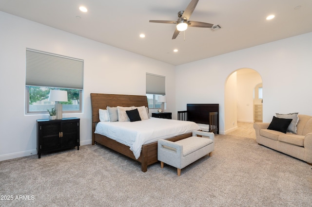 bedroom with light carpet, visible vents, arched walkways, and recessed lighting