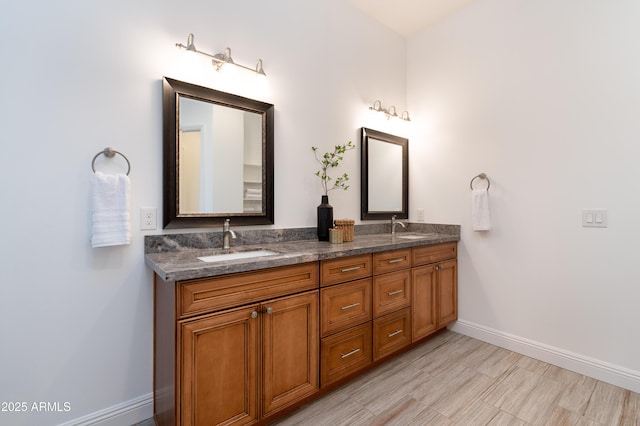 full bath with double vanity, baseboards, and a sink