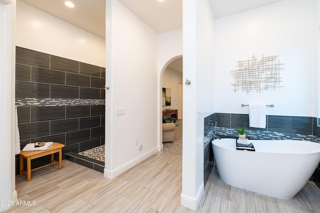 full bathroom featuring a soaking tub, wood tiled floor, a walk in shower, and tile walls