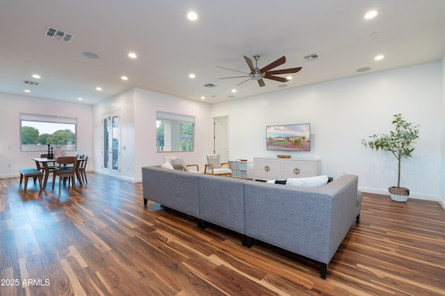 living area featuring dark wood-style flooring, visible vents, and a healthy amount of sunlight