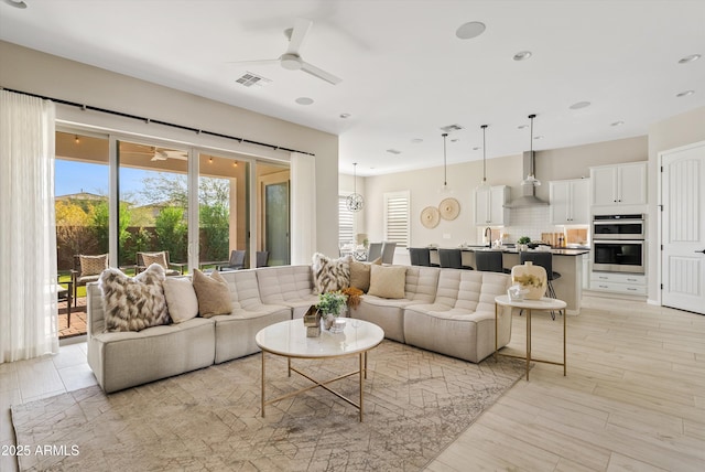 living room with light hardwood / wood-style flooring, ceiling fan, and sink