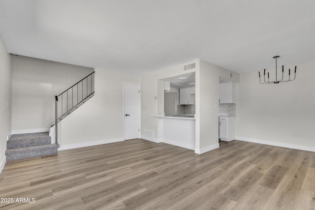 4714 E Broadway Rd, Phoenix, AZ 85040 - unfurnished living room with a chandelier, light wood-style flooring, stairs, and baseboards