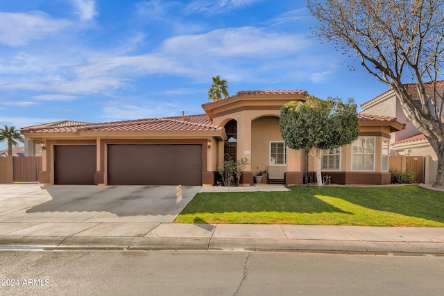 mediterranean / spanish-style home with a garage and a front lawn