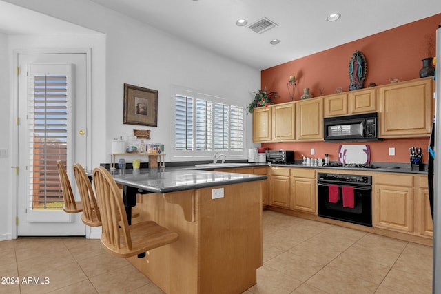 kitchen featuring light tile patterned flooring, sink, a kitchen breakfast bar, black appliances, and light brown cabinets