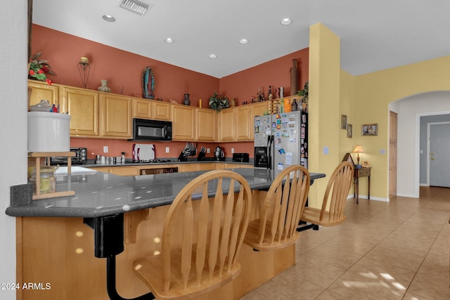 kitchen with a kitchen breakfast bar, stainless steel refrigerator with ice dispenser, and kitchen peninsula