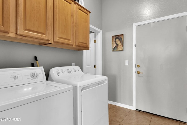 clothes washing area with light tile patterned floors, cabinets, and washer and dryer