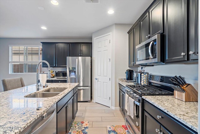 kitchen featuring light hardwood / wood-style floors, light stone counters, sink, and appliances with stainless steel finishes