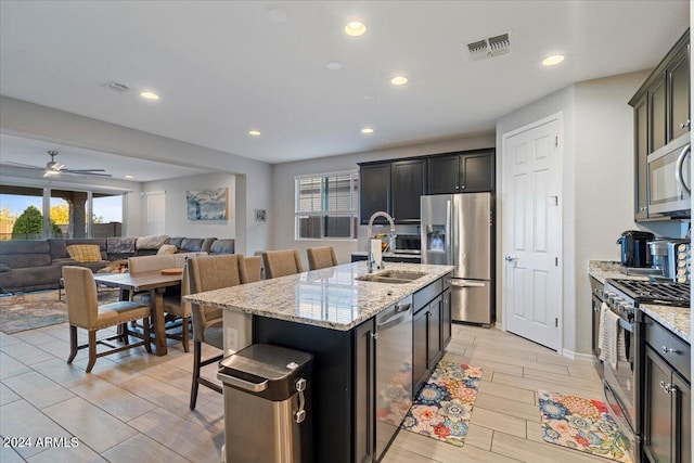 kitchen with appliances with stainless steel finishes, a center island with sink, plenty of natural light, and sink