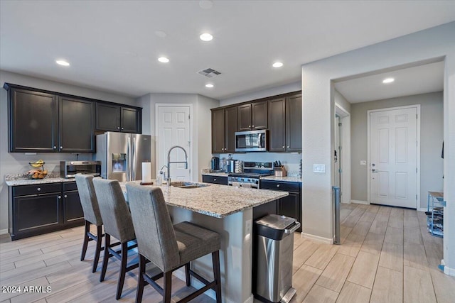 kitchen featuring sink, light hardwood / wood-style flooring, a breakfast bar area, a center island with sink, and appliances with stainless steel finishes