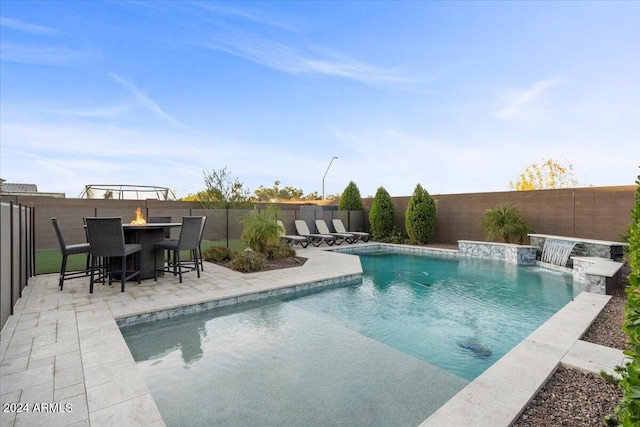 view of pool with a patio area, pool water feature, and an outdoor fire pit