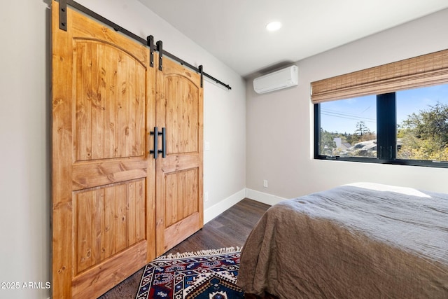 bedroom with a wall mounted AC, recessed lighting, baseboards, dark wood finished floors, and a barn door
