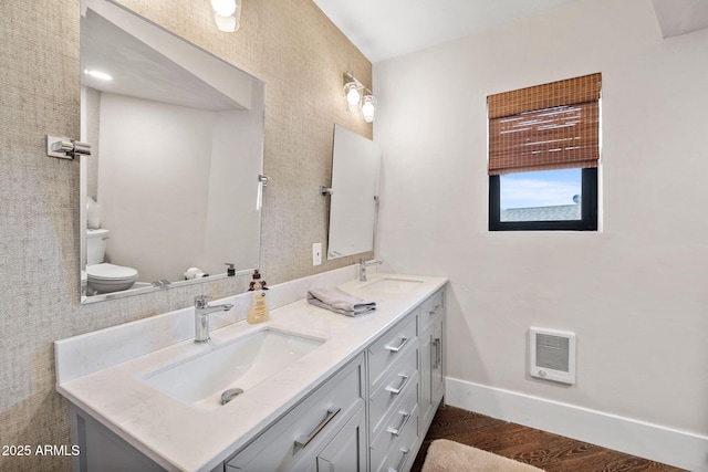 full bath with baseboards, double vanity, a sink, and toilet