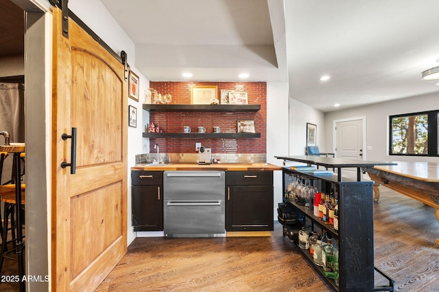 bar featuring wet bar, a barn door, wood finished floors, and recessed lighting
