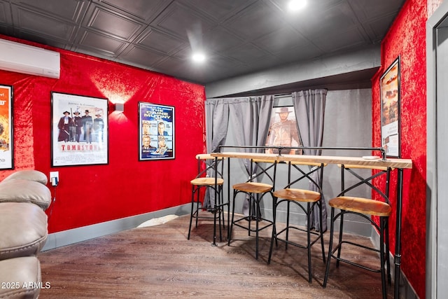 interior space with a wall mounted AC, an ornate ceiling, baseboards, and wood finished floors