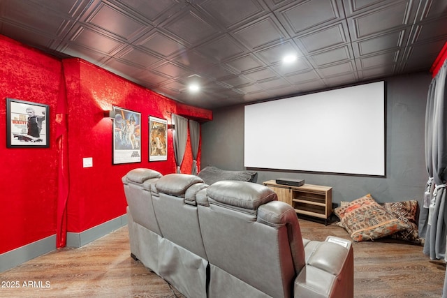 home theater featuring an ornate ceiling, baseboards, and wood finished floors