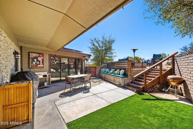 view of patio featuring grilling area, fence, and stairway