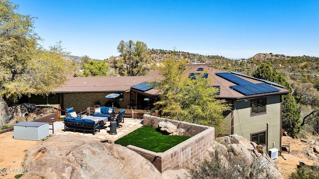 exterior space with outdoor lounge area, a lawn, solar panels, and a patio area