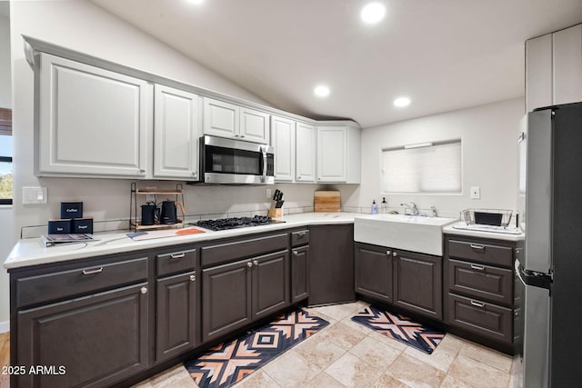 kitchen with light countertops, recessed lighting, appliances with stainless steel finishes, white cabinetry, and a sink