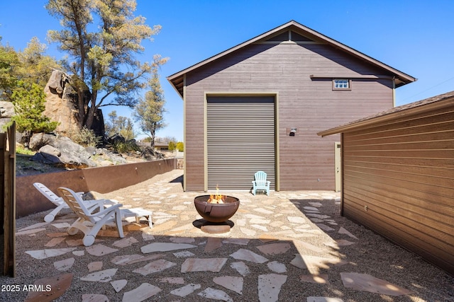 exterior space featuring a fire pit, an outdoor structure, and fence