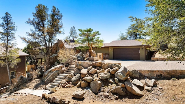 view of front of house with driveway, an attached garage, and stairs