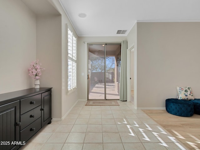 doorway featuring a wealth of natural light, ornamental molding, and light tile patterned floors