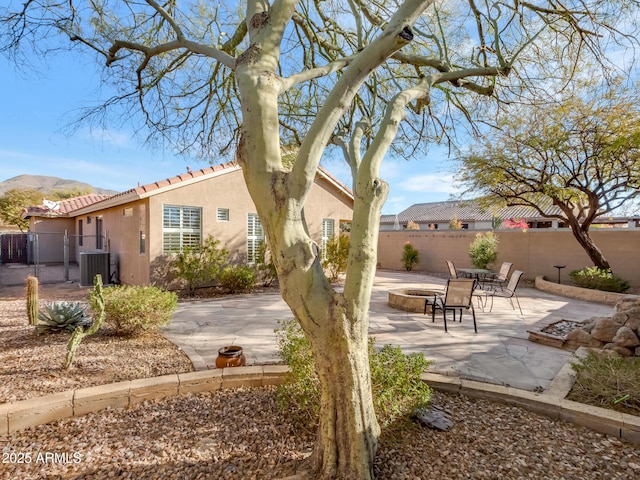 view of front of property featuring a mountain view, an outdoor fire pit, central AC unit, and a patio area