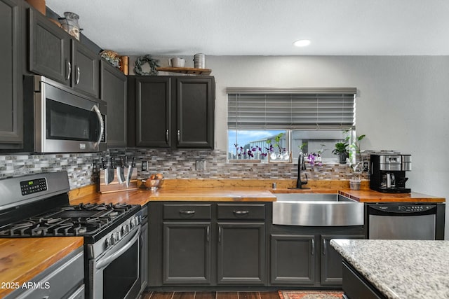 kitchen with stainless steel appliances, tasteful backsplash, sink, and wooden counters