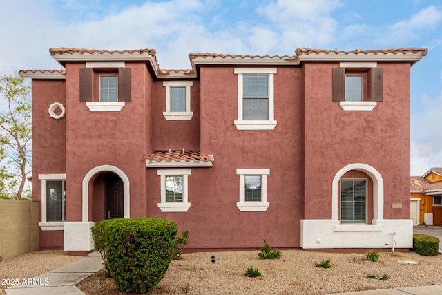 mediterranean / spanish house featuring fence and stucco siding