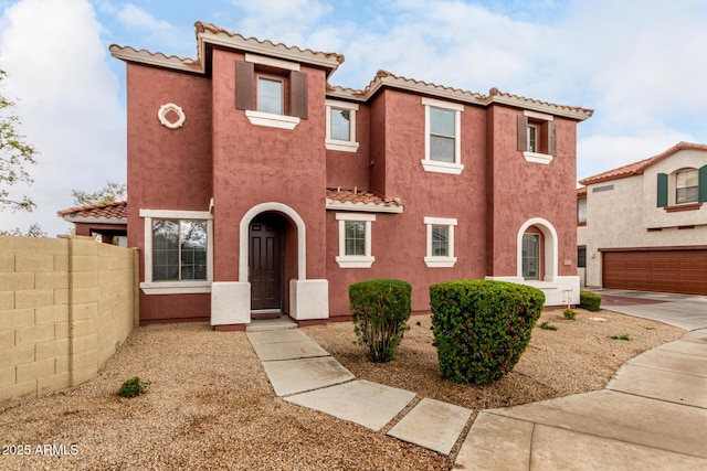 mediterranean / spanish-style home with a tile roof, fence, and stucco siding